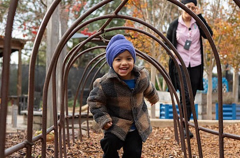 young boy running through a tunnel outside