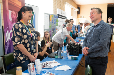 An exhibitor chats with a visitor in a hall during an event