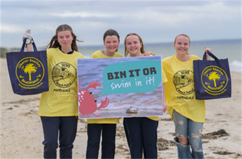 Four young girls holding a sign on the beach