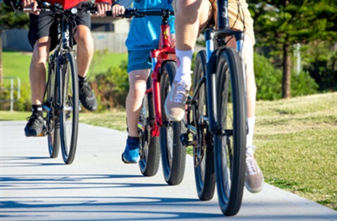 3 cyclists riding their bikes along a bike path