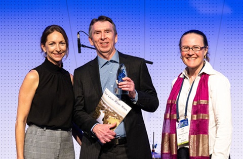 Man being presented with an award by two women.