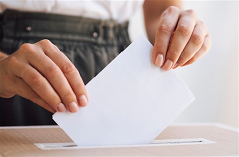 Folded ballot paper being placed into a box.