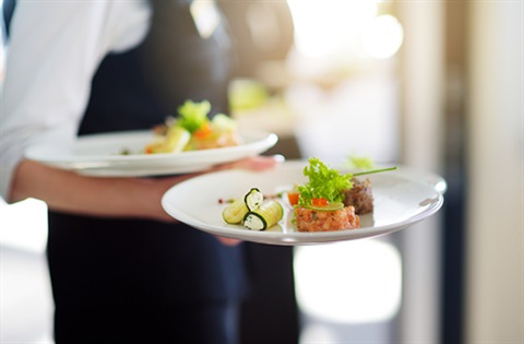 Waitress holding plates of food in a restaurant.