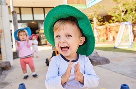 Small boy with green hat playing outside.